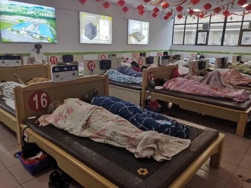 ▲9月24日，可喜安郑州凌云路店内，老人们躺在治疗仪上进行体验。新京报记者 程亚龙 摄